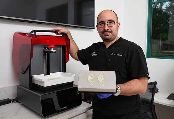 Murias Dental dentist holding 3D printed dental models from in-house lab