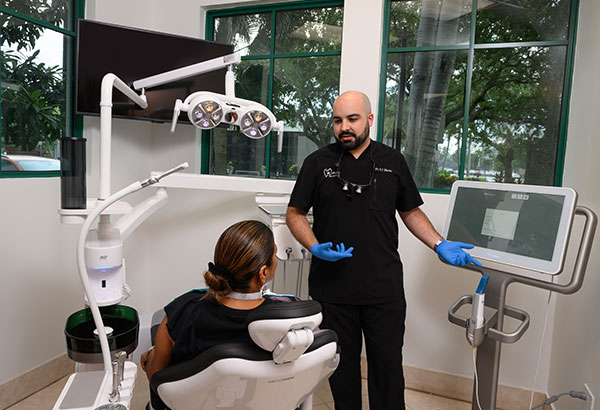 Murias Dental dentist explaining dental exam reports to patient using digital design technology