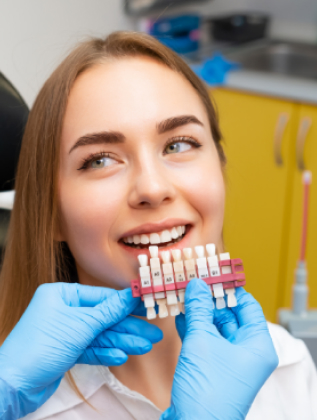Patient smiling while shade matching for porcelain veneers and crowns at Murias Dental cosmetic dentistry